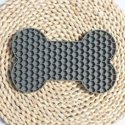 Dog Lick Mat in a bone shape made of black food-grade silicone, perfect for slowing down fast eaters. - Whiskerwise